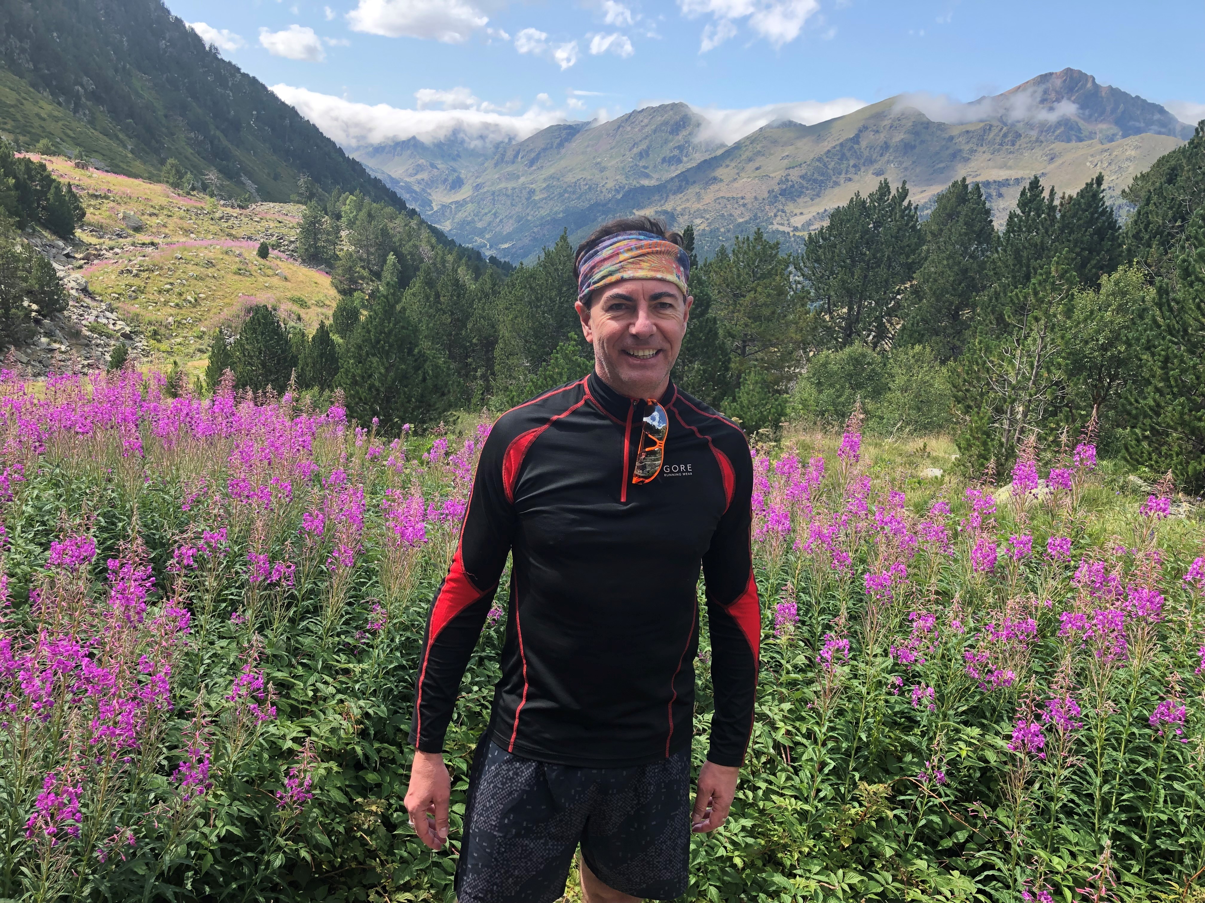 Inspiración en la naturaleza: Juan en un paisaje montañoso rodeado de flores violetas.